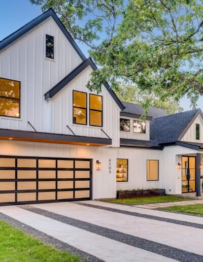 Modern two-story suburban home at dusk with illuminated windows and a double garage.