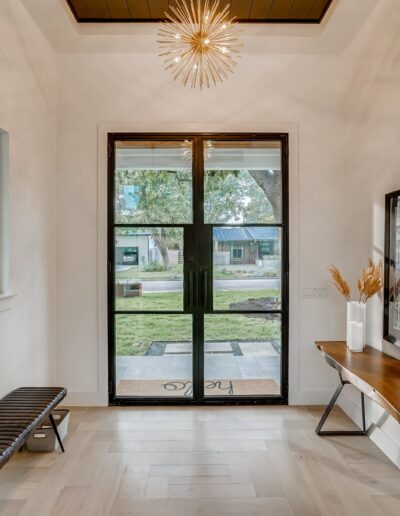 Bright and modern entryway with a bench, console table, and an ornate light fixture.