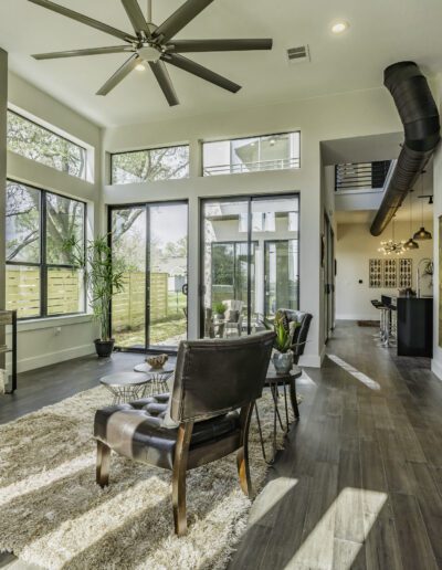 Modern living room with high ceilings, large windows, and a staircase.