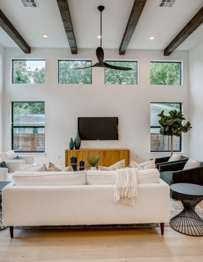 Modern living room with white sofa, high ceilings, and large windows.