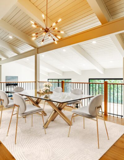 Modern dining room with high ceiling, large windows, and a starburst chandelier.