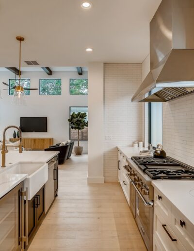 Modern kitchen interior with stainless steel appliances, white marble countertops, and ample natural light.