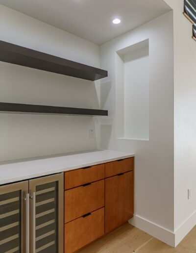 A modern understairs space featuring floating shelves, wooden cabinets, and a view of the backyard.