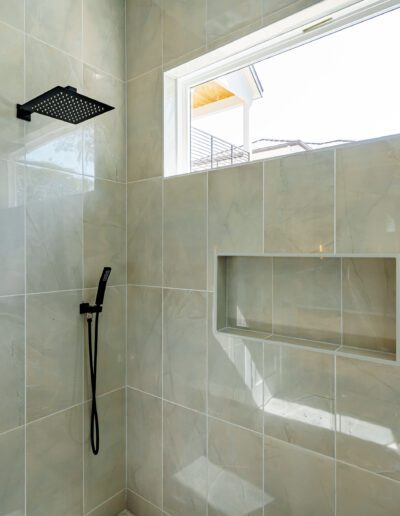 Modern bathroom with a glass shower enclosure and marble tiles.