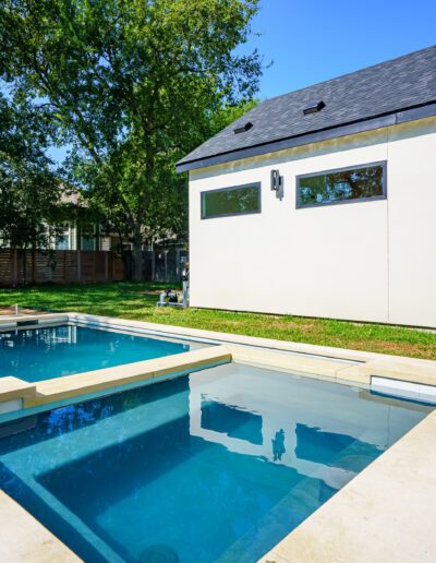 Modern backyard with a swimming pool and spa near a contemporary house.