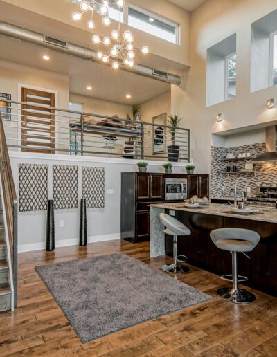 A modern kitchen with breakfast bar, adjoining dining area, and staircase leading to an upper level.