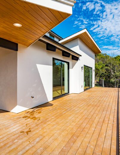 Modern house with a spacious wooden deck and clear blue sky.