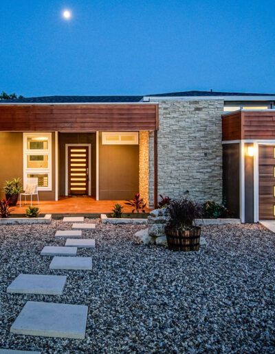 Modern home exterior at twilight with illuminated pathway and garage door.