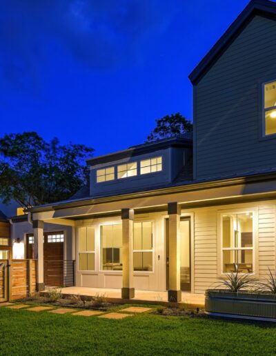 A modern two-story house with illuminated windows at twilight.