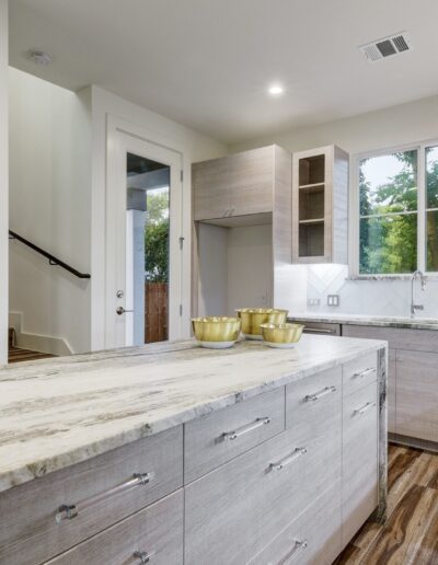 Modern kitchen interior with wooden cabinets and marble countertops.