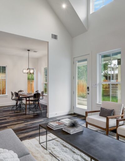 Modern living room with high ceilings, adjacent dining area, and large windows.