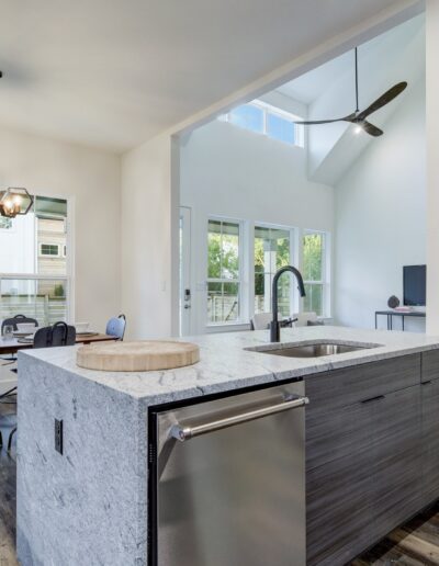 Modern kitchen with a breakfast bar, adjoining dining area, and a view of a staircase.