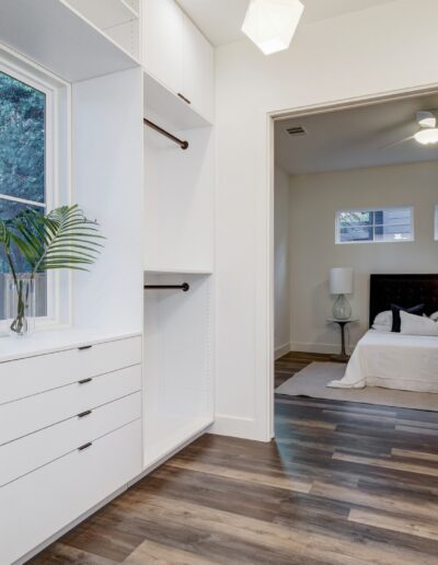 Walk-in closet with built-in shelves and drawers, leading to a bedroom.